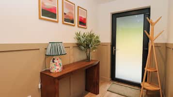 A hallway with a wooden console table, a lamp, a plant, and three framed pictures on the wall.