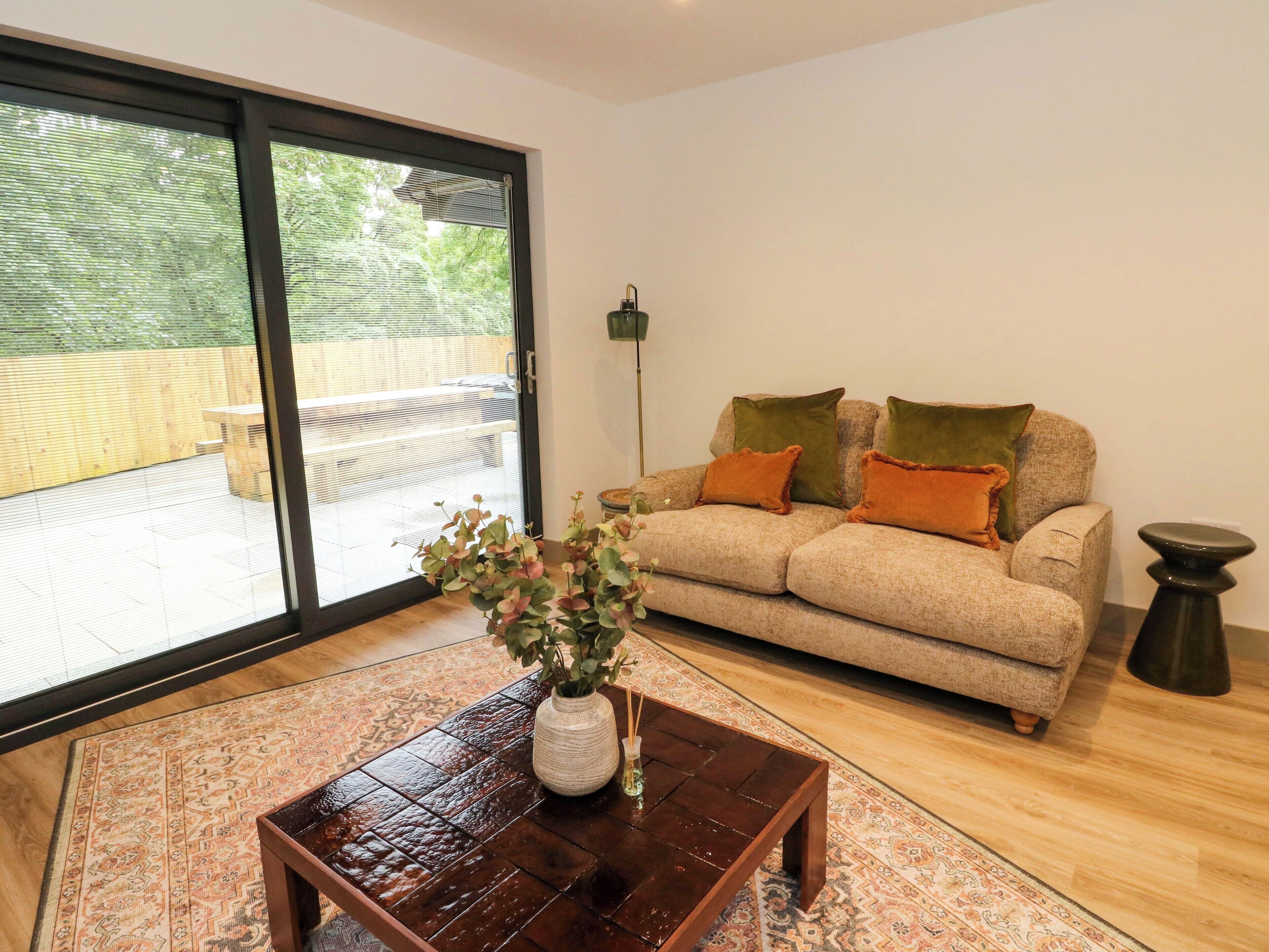 A living room with a sofa, a coffee table, and a view through a sliding glass door.