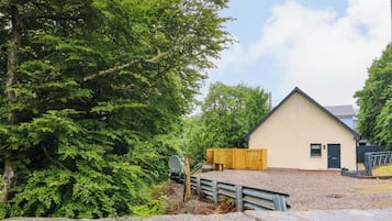 Uma casa com telhado inclinado, um pequeno alpendre e uma entrada com calçamento de pedras.