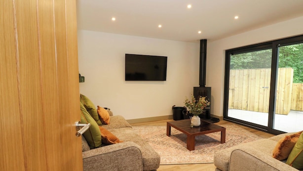 A modern living room with two sofas, a coffee table, a flat-screen TV, and a large window. - Nevis Bridge House (Fort William)