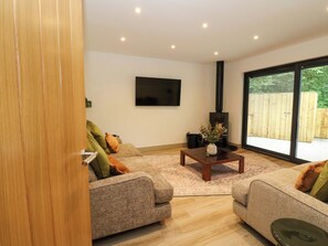 A modern living room with two sofas, a coffee table, a flat-screen TV, and a large window. - Nevis Bridge House (Fort William)