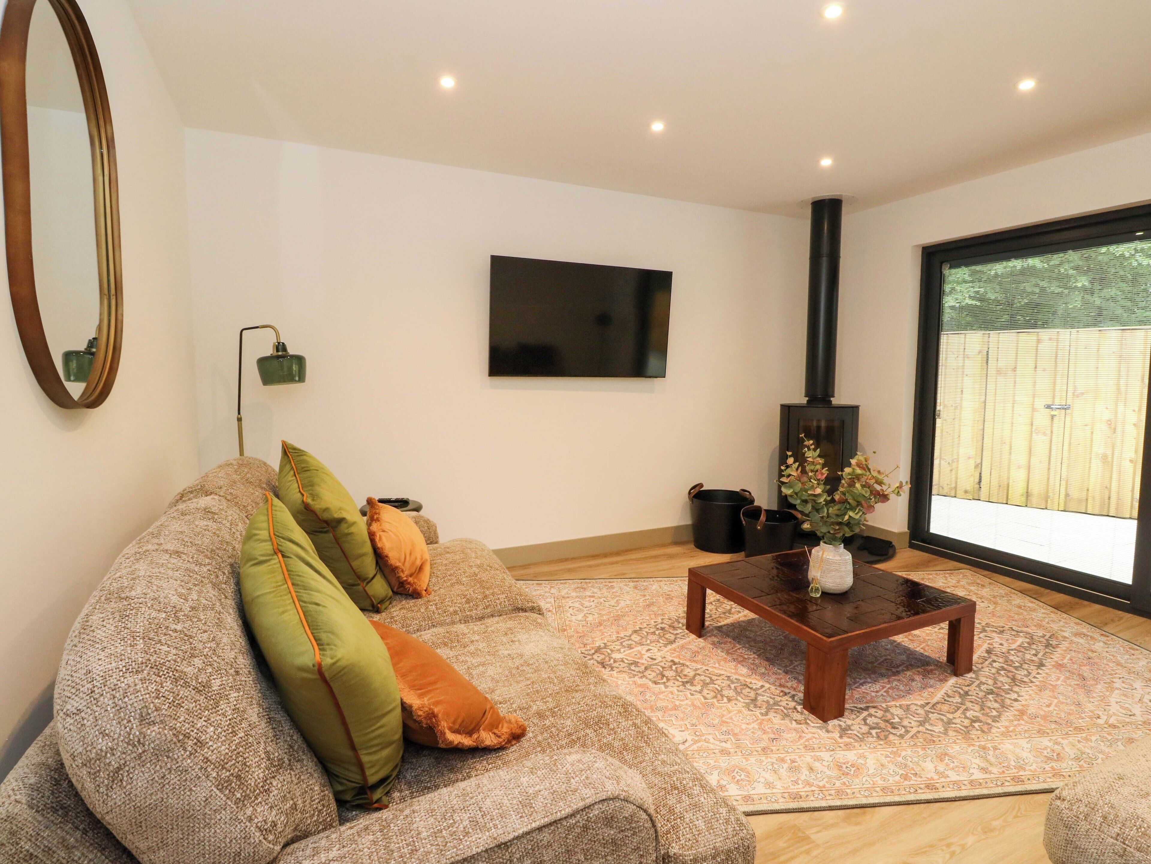 A living room with a sofa, a coffee table, a flat-screen TV, a fireplace, and a large window.