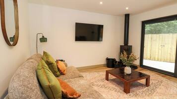 A living room with a sofa, a coffee table, a flat-screen TV, a fireplace, and a large window.