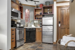 Una cocina con electrodomésticos de acero inoxidable, gabinetes de madera y salpicadero de azulejos.