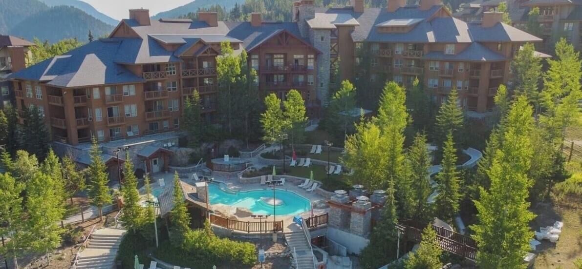 A resort with multiple buildings, a central pool area, and surrounding greenery.