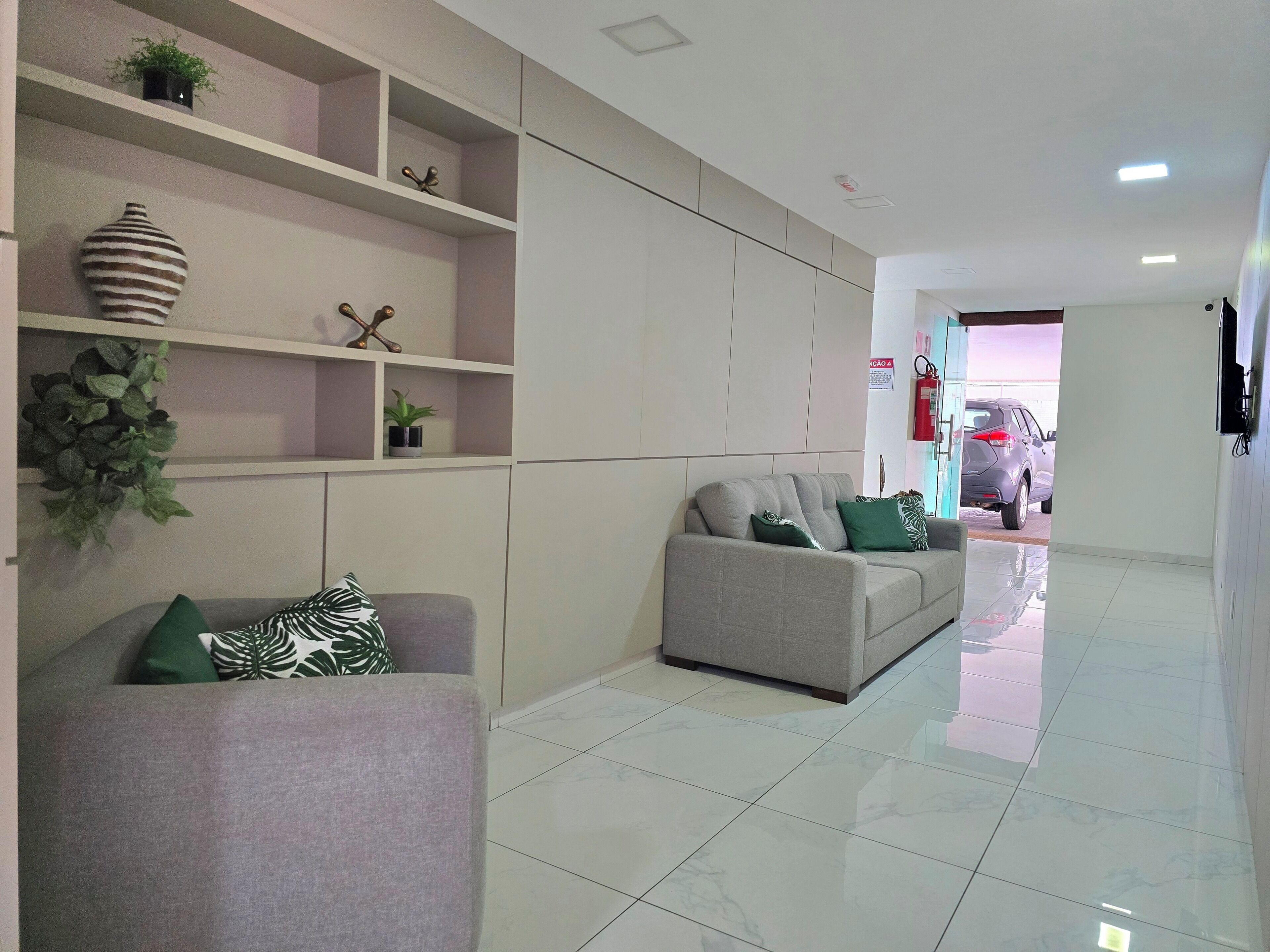 A modern living room with a sofa, a coffee table, and decorative items on shelves.