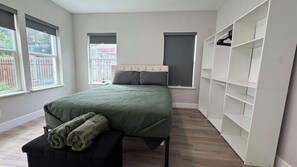 A bedroom with a bed, a bench with towels, a wardrobe, and two windows. - Houston House 5 mins TMC, & Near NRG/Downtown (Houston)