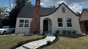 A two-story house with a brick chimney, a front entrance with a door, and a driveway leading to a parked car. - Houston House 5 mins TMC, & Near NRG/Downtown (Houston)