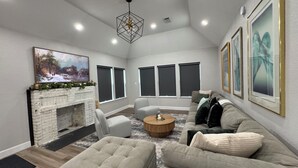 A modern living room with a fireplace, comfortable seating, large windows, and artwork on the walls. - Houston House 5 mins TMC, & Near NRG/Downtown (Houston)