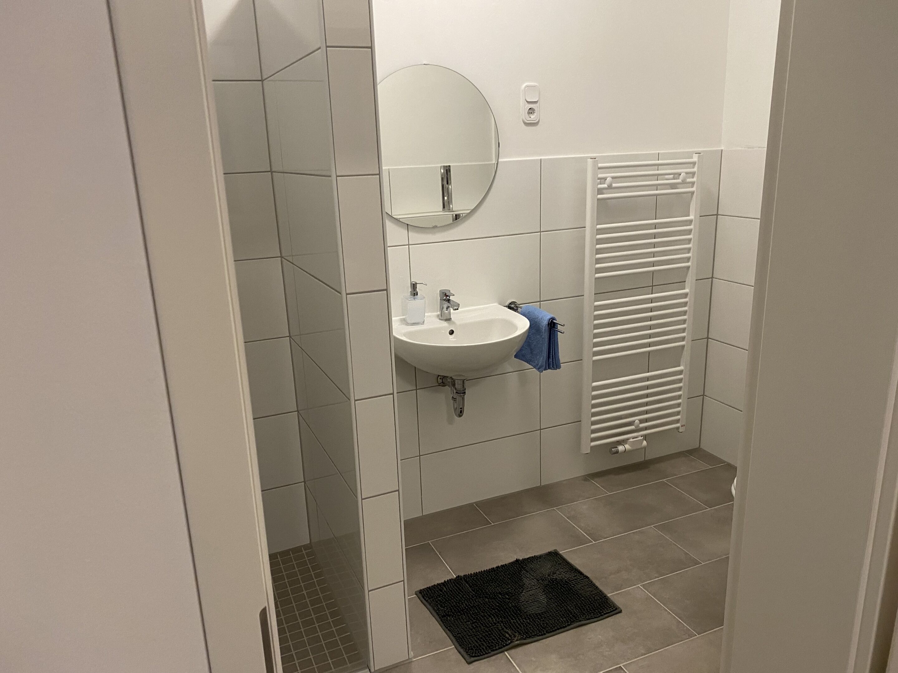 A bathroom with a white sink, mirror, and towel rack.