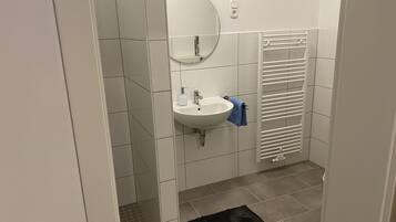 A bathroom with a white sink, mirror, and towel rack.