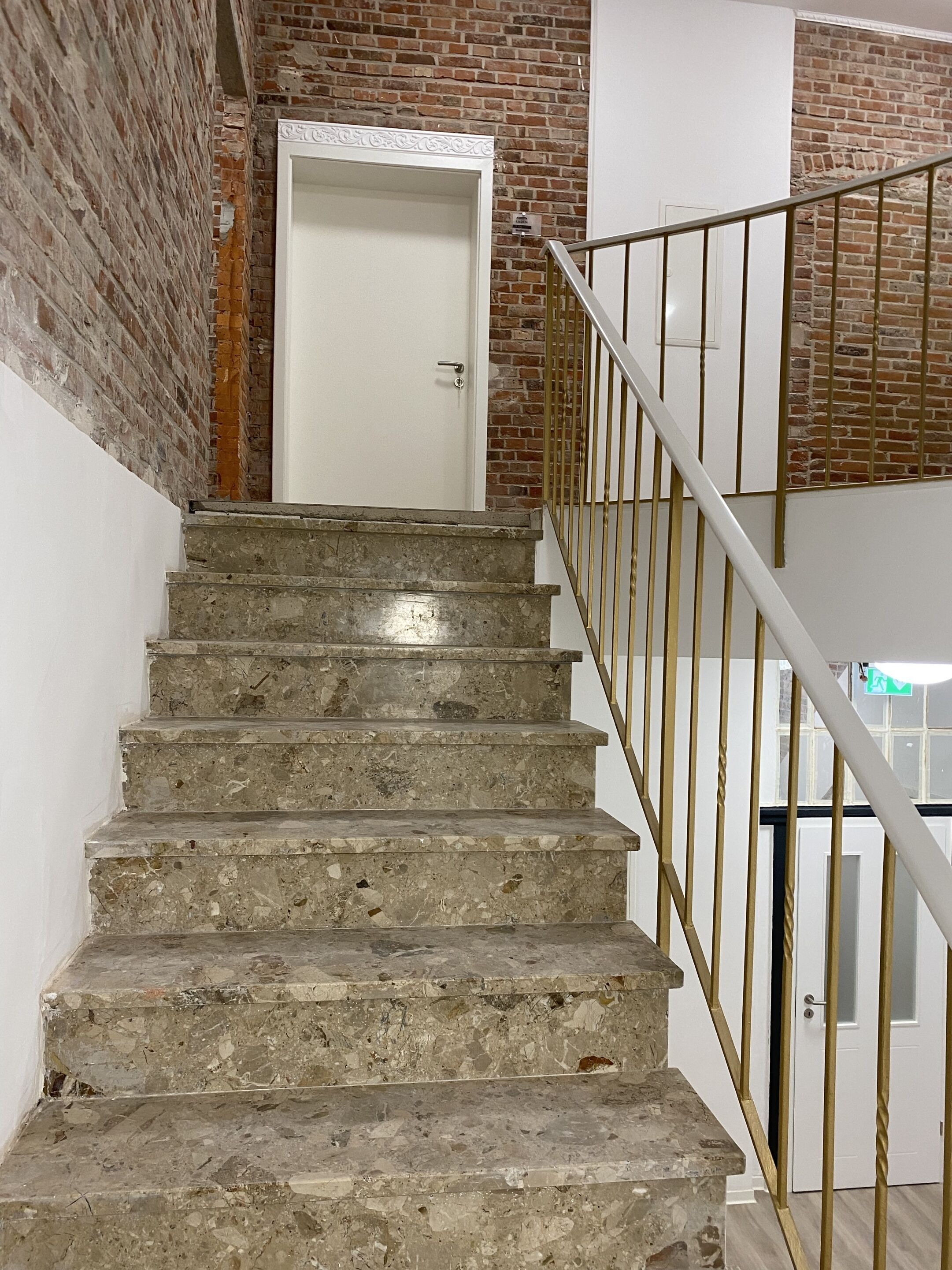A staircase with a marble finish, leading to a white door with a decorative trim.