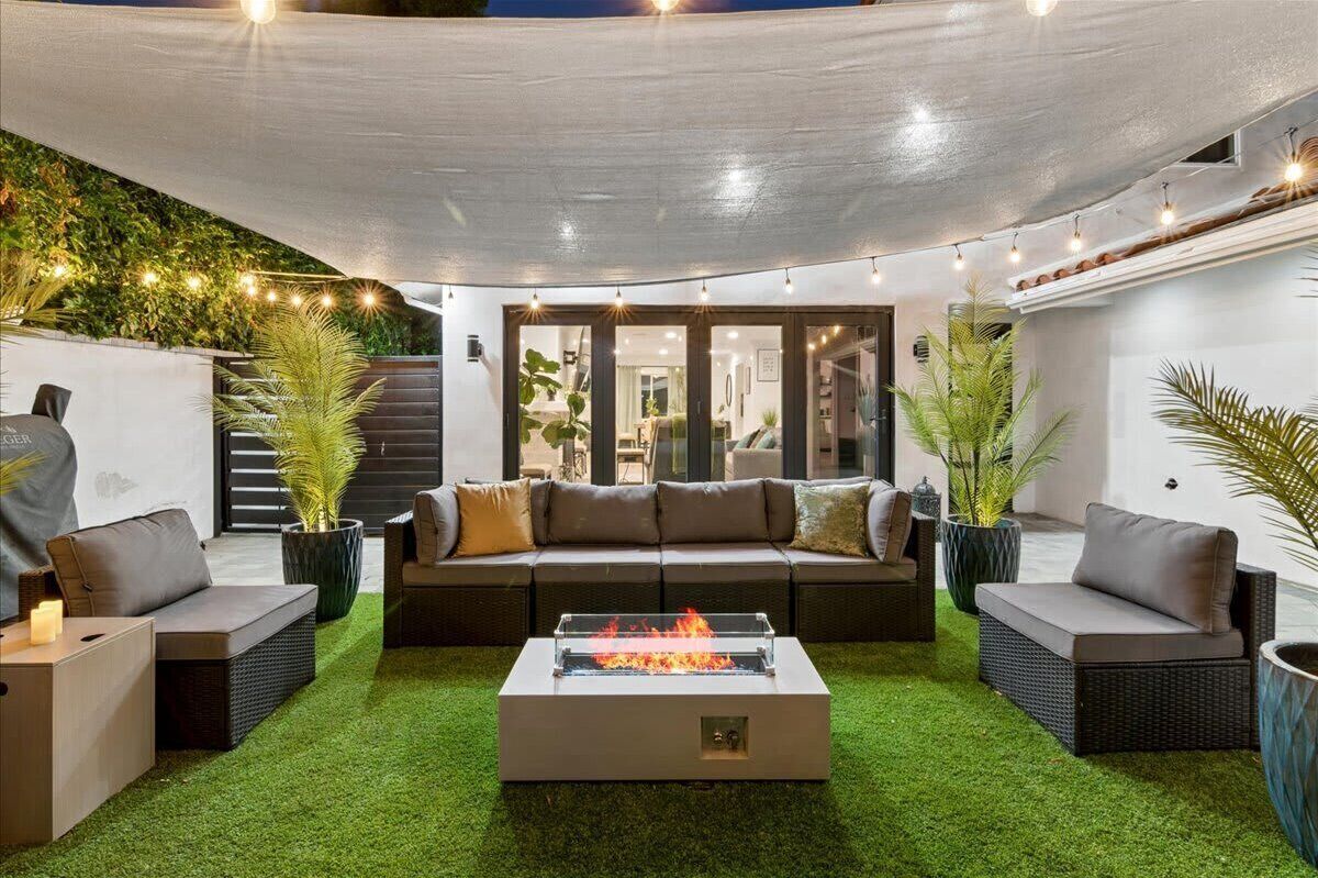 An outdoor living area with a fire pit, seating, and a covered patio.