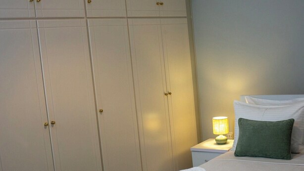 Ett hotellrum med en sÀng, ett nattduksbord med en lampa, en grön kudde och en hög med handdukar.