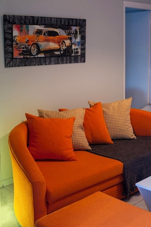 A modern living room with a sofa and matching cushions, a framed artwork above the sofa, and a door to the right. - 🏠 Zografou Urban Nest! (Zografou)