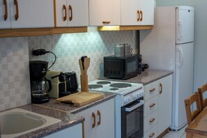 A kitchen with white cabinets, a stove, a microwave, a coffee maker, and a refrigerator. - 🏠 Zografou Urban Nest! (Zografou)