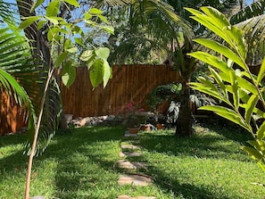Un jardín con cerca de madera, un sendero de piedra y diversas plantas.
