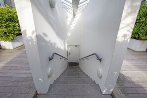 Una escalera con barandillas metálicas y una pared blanca.