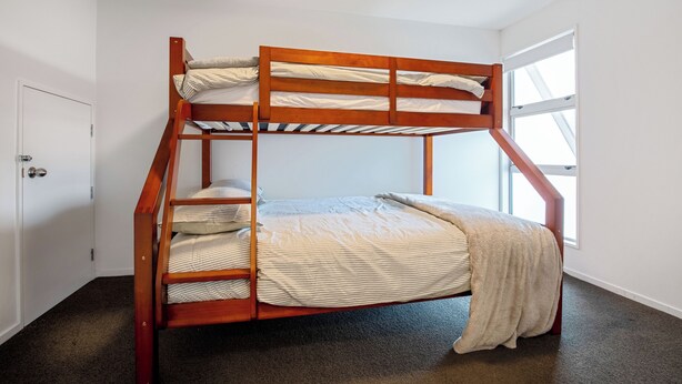 Una cama litera en una habitación con una puerta y un ventanal.