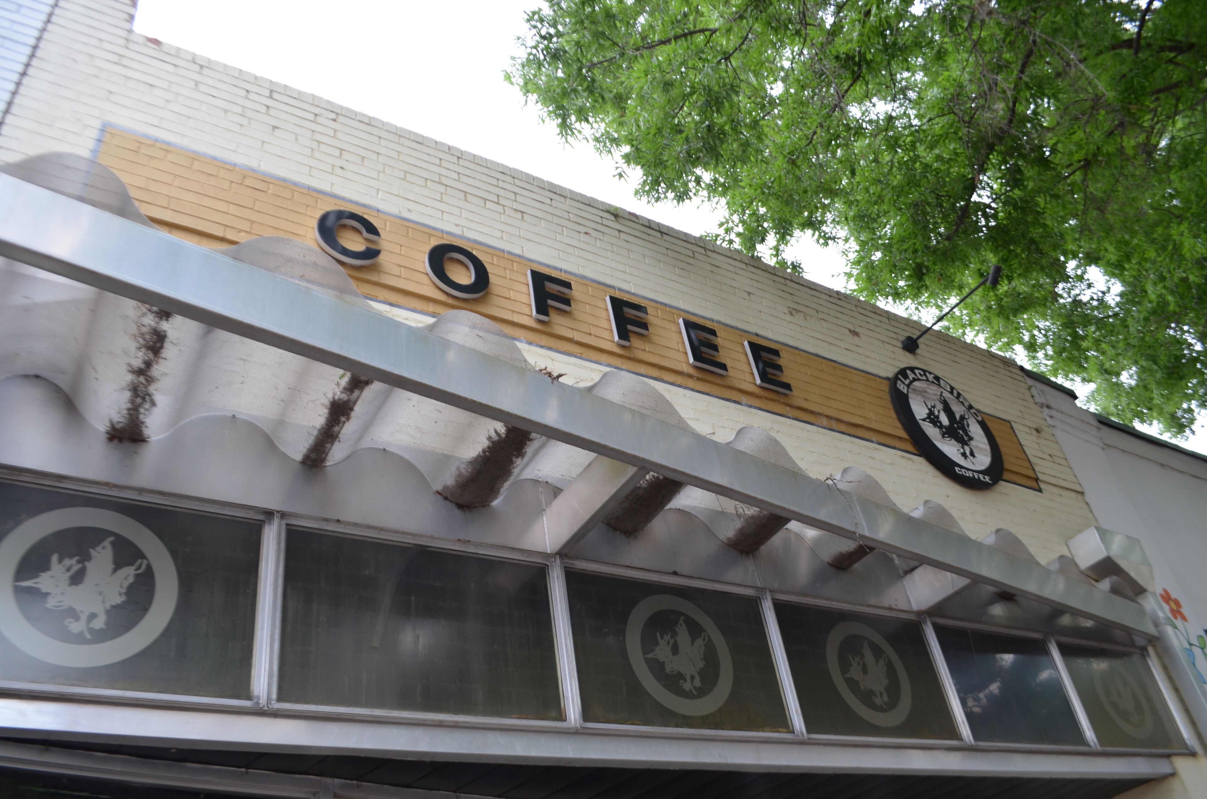 A storefront with a sign that reads 'COFFEE' and a logo above it.