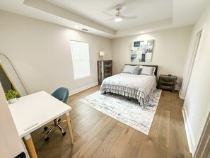 A bedroom with a bed, bedside tables, a desk, and a chair.