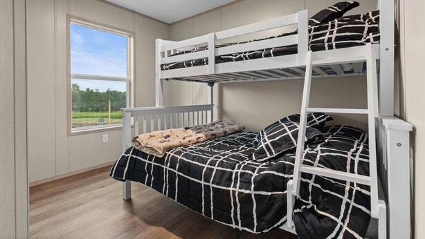 Een slaapkamer met een stapelbed, een raam en uitzicht op groen.