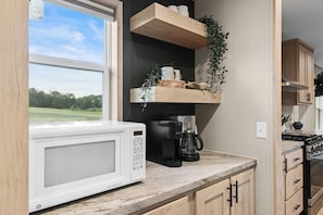A kitchen with a microwave, coffee maker, and wooden cabinets. - Hot Tub Retreat on 190-Acre Farm · Sleeps 6 (Lakewood)