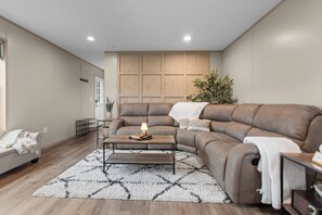 Ein modernes Wohnzimmer mit einem Ecksofa, einem Couchtisch und einem Teppich.