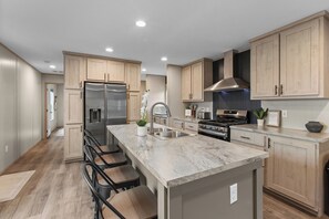 Una cocina moderna con una isla central, electrodomésticos de acero inoxidable y armarios de madera clara.