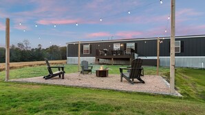 Een achtertuin met een vuurkorf, buitenmeubilair en een terras.