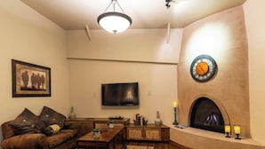 A living room with a fireplace, a television, and a sofa. - Inn at Gard Estate Wines (Prosser)