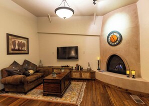 Una sala de estar con chimenea, televisor y sofá.