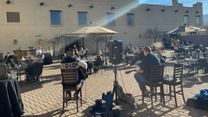 An outdoor patio area with tables and chairs, a stage with musical equipment, and string lights. - Inn at Gard Estate Wines (Prosser)
