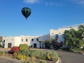 Un edificio blanco con cielo despejado y un globo aerostático a lo lejos.