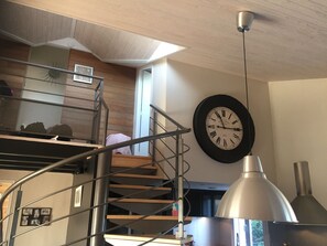 A staircase with a metal railing, a wall-mounted clock, and a pendant light fixture. - Beautiful house nearby is operational (La Teste-de-Buch)