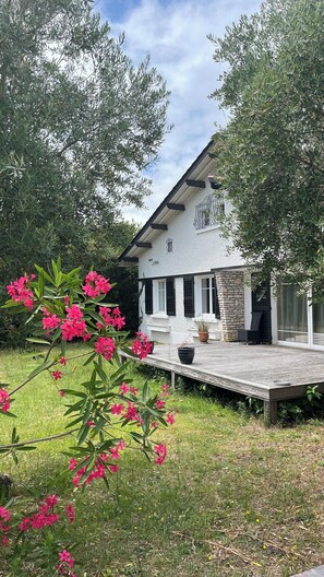 A house with a stone facade, a wooden deck, and a garden with pink flowers. - Beautiful house nearby is operational (La Teste-de-Buch)