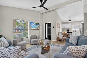 Ein modernes Wohnzimmer mit einem Glastisch, grauen Sofas und einem Deckenventilator.