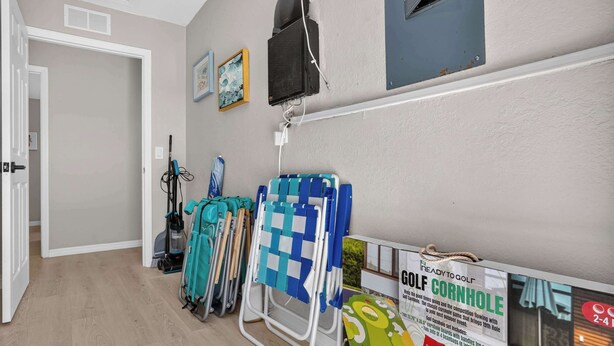 A room with a door, a vacuum cleaner, a golf cart, and a sign for a golf course. - Modern Hacienda | 3BR, Fenced Yard, Beach Gear, Dog-Friendly, Near Downtown (Sarasota)