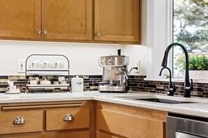 Une cuisine moderne avec des meubles en bois, une machine à café et un évier doté d’un robinet noir.