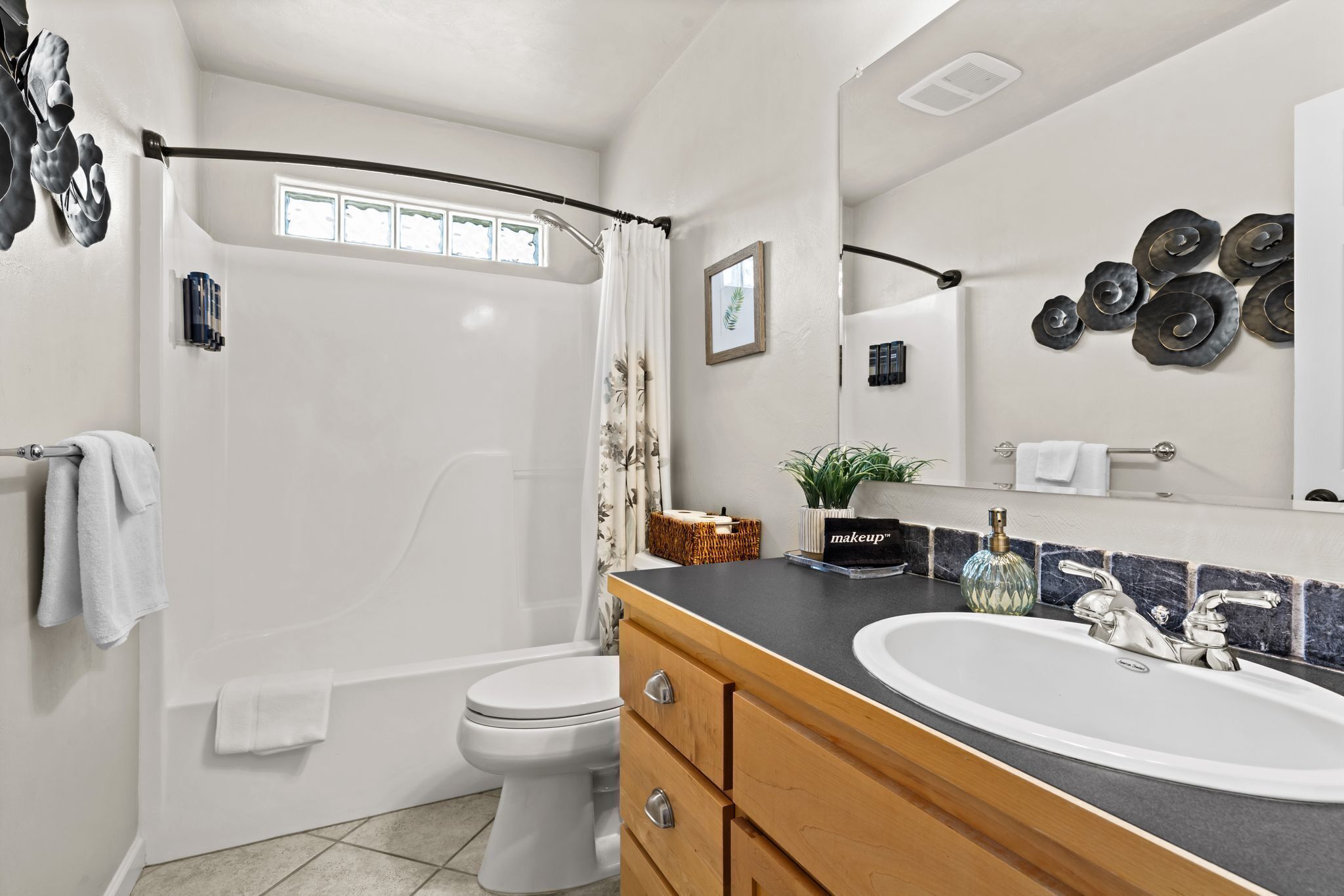 A modern bathroom with a shower, toilet, vanity with a sink, and a large mirror.