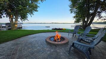 Une terrasse extérieure avec un foyer, des sièges et une vue sur un lac.