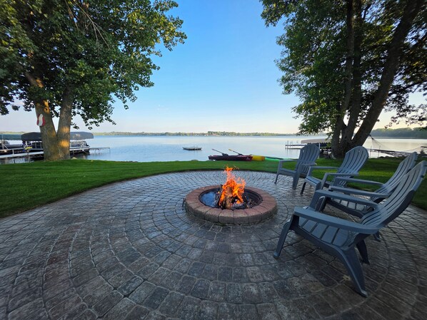 An outdoor patio with a fire pit, seating, and a view of a lake.