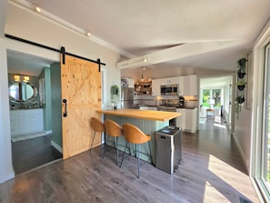 A modern kitchen with a central island, bar stools, and a sliding barn door.