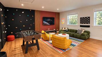 A modern living room with a foosball table, a sofa, and a colorful rug.