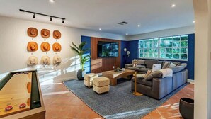 A modern living room with a sofa, coffee table, and a wall-mounted television. - 2-Acre Estate: Private Padel Court + Par-3 Golf (Davie)