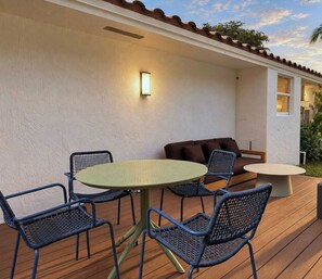 An outdoor patio with a round table and chairs, a sofa, and a wall-mounted light fixture. - Hot-Tub, Pool, Golf, Pickleball, Basketball | Casa (Davie)