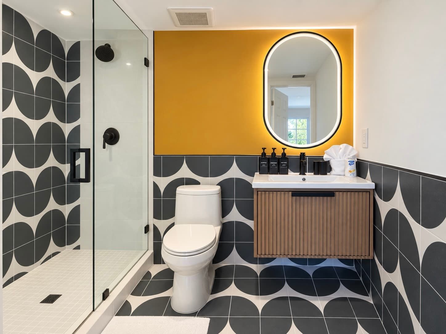 A modern bathroom with a glass shower enclosure, a white toilet, and a vanity with a mirror.