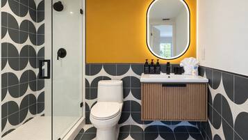 A modern bathroom with a glass shower enclosure, a white toilet, and a vanity with a mirror.