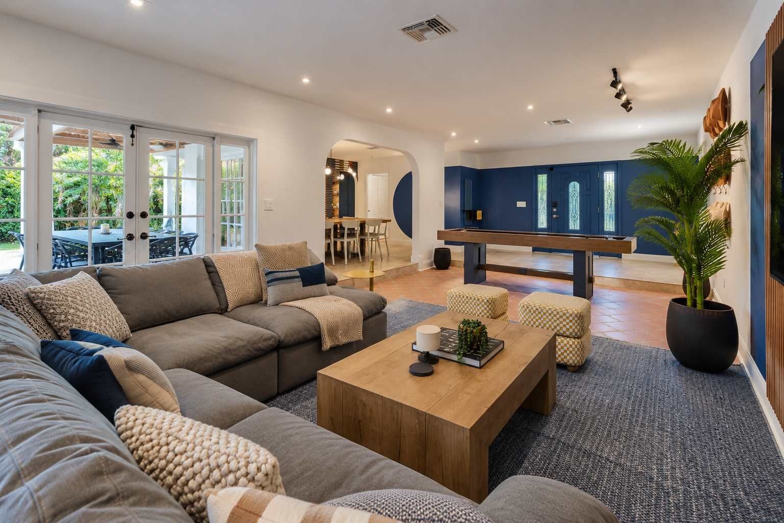 A modern living room with a sectional sofa, a coffee table, and a dining area with a bench.