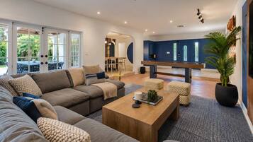A modern living room with a sectional sofa, a coffee table, and a dining area with a bench.